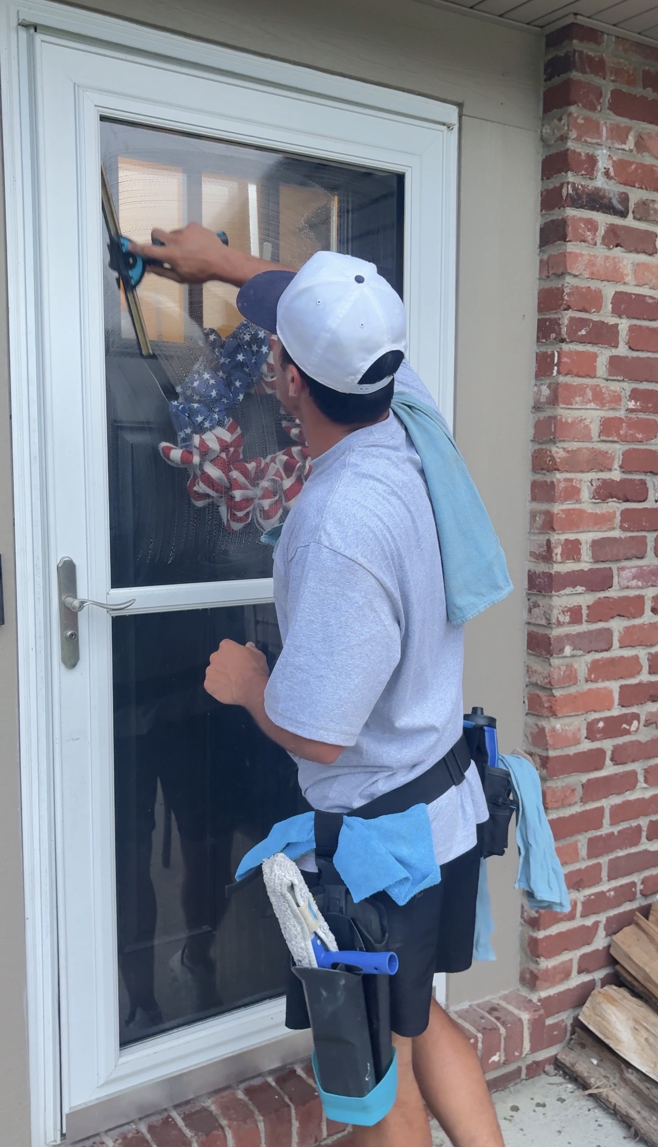 DeMoss technician cleaning a glass storm door with a squeegee
