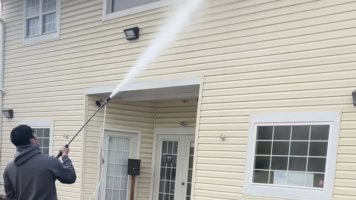 DeMoss technician soft-washing the siding of a home