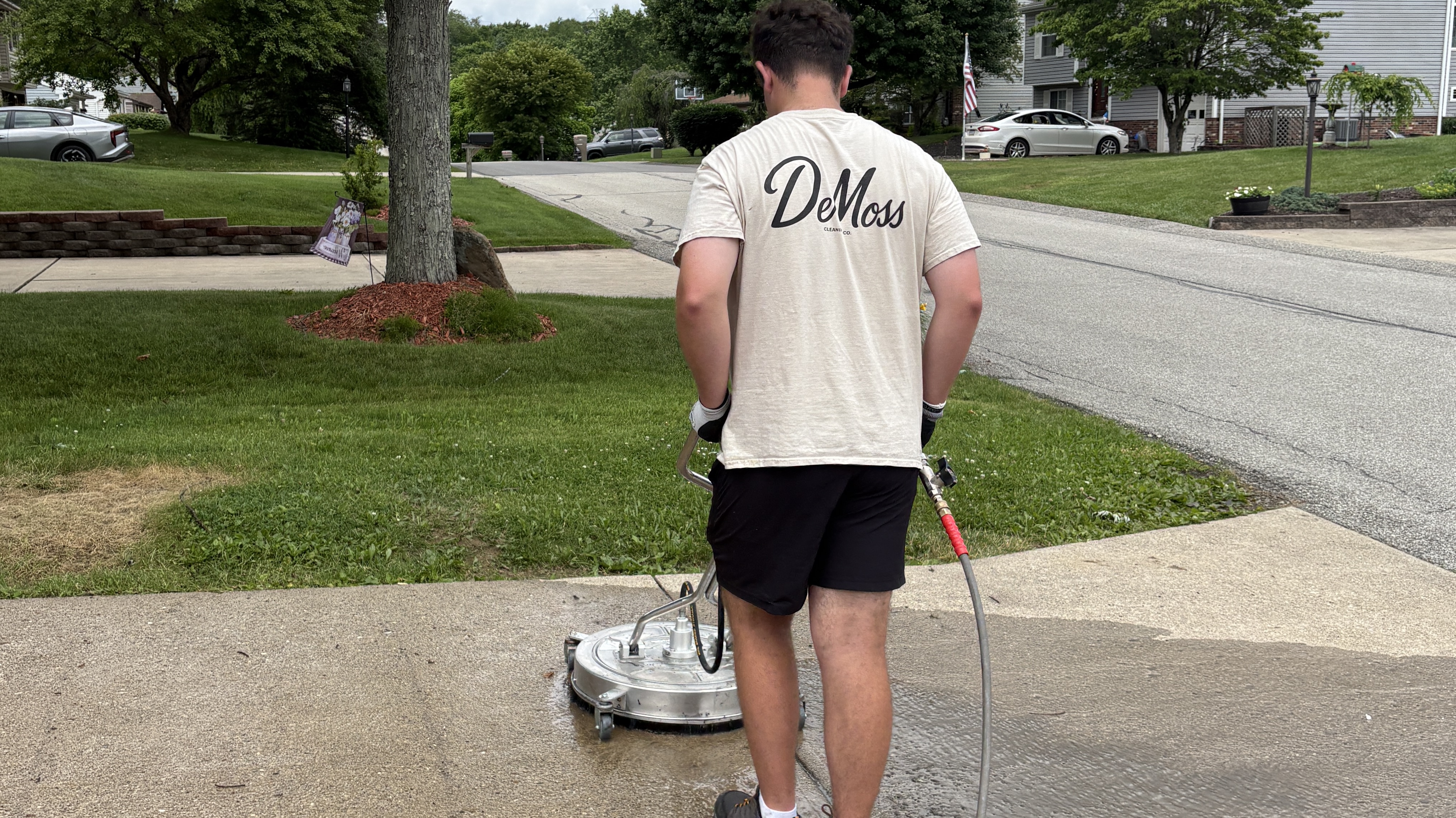 DeMoss Cleaning Co. technician surface-cleaning a concrete driveway