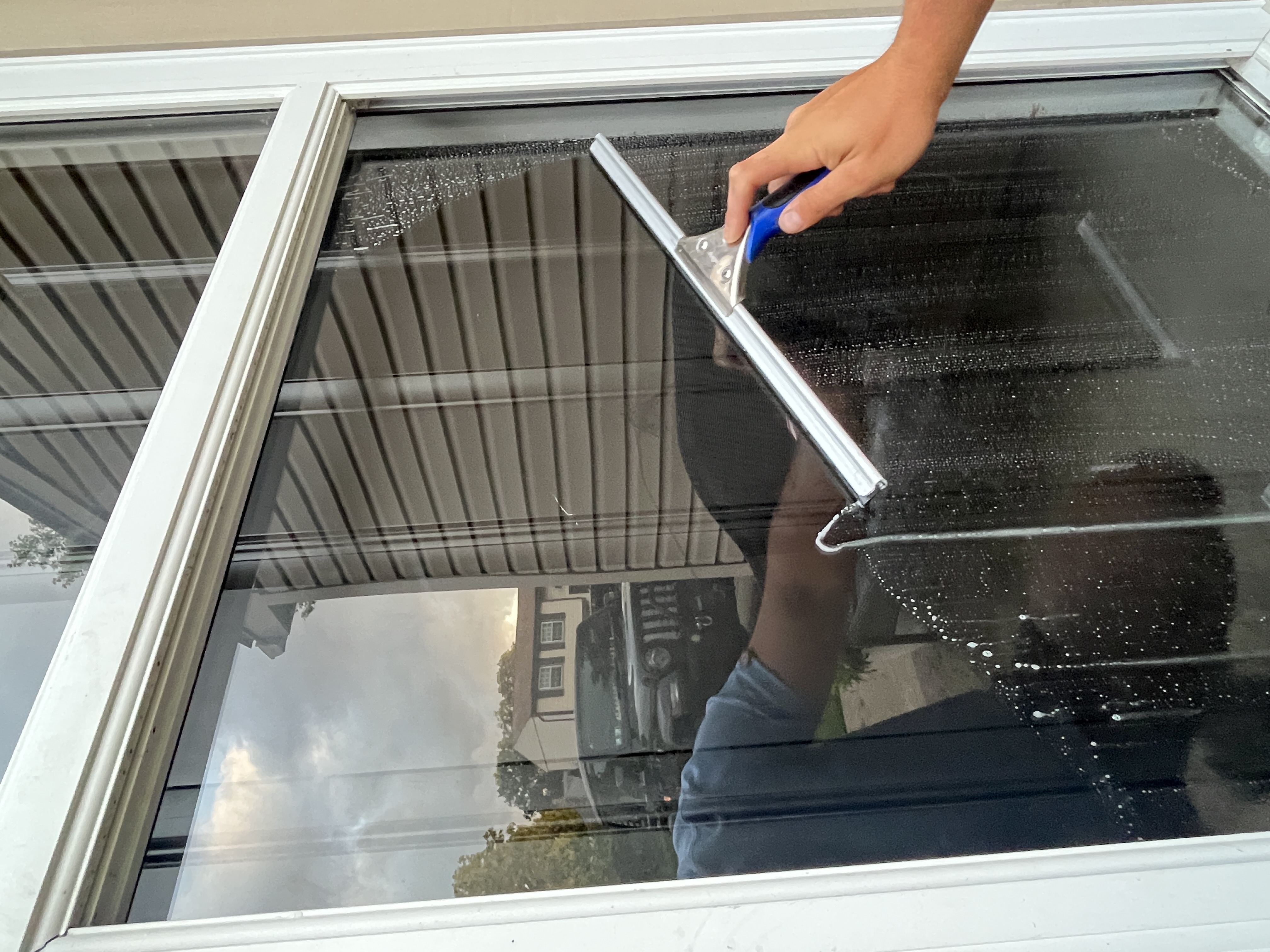 DeMoss technician making a squeegee pass across a window